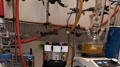 Laboratory equipment including a round-bottom flask in a water bath with stirrer